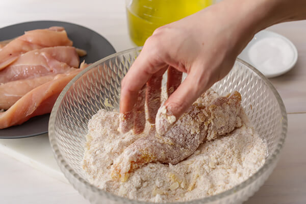 Breading chicken tenders in the keto flour mixture.