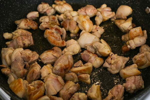 Frying the chicken pieces in a skillet.