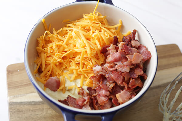 Bread batter in a bowl with cheese and bacon on top.
