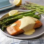 Plated salmon and asparagus recipe with hollandaise sauce on top.