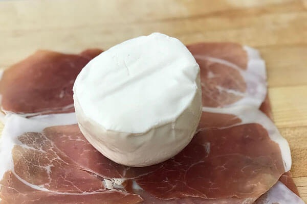 Prosciutto slices with mozzarella ball on top.