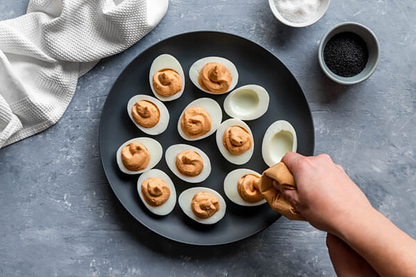 Adding the egg filling to each of the eggs.