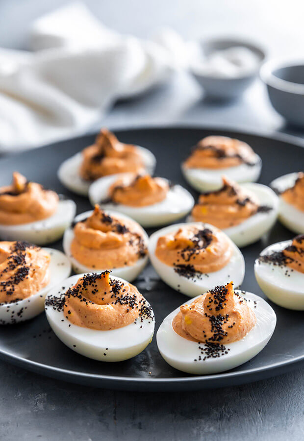 Spicy keto deviled eggs made with red curry paste and topped with poppy seeds.