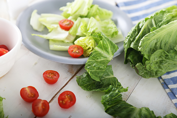 Chopped romaine lettuce and halved cherry tomatoes on a plate and cutting board