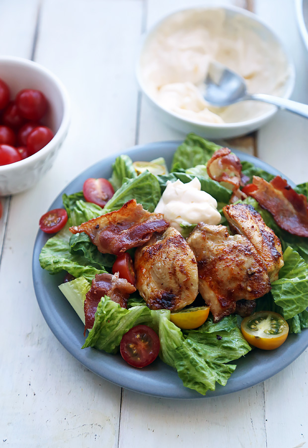 BLT salad with browned chicken thighs, bacon, cherry tomatoes, and garlic mayo on romaine
