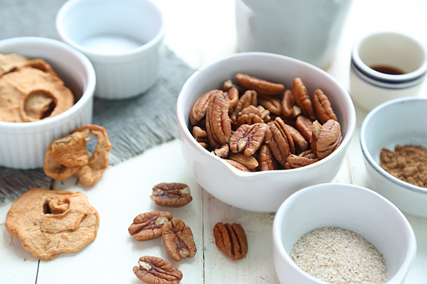 Pecans, freeze dried apples, psyllium husk, pumpkin pie spice, and coconut butter in small bowls