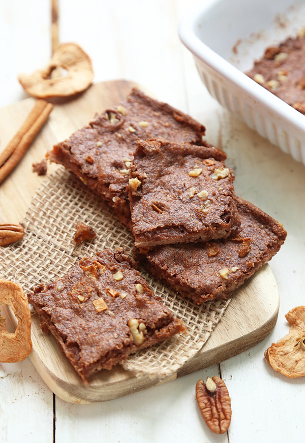 Baked apple cinnamon breakfast bars with pecan pieces on a wooden cutting board