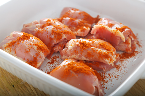 Raw chicken thighs dusted with paprika in a white baking dish