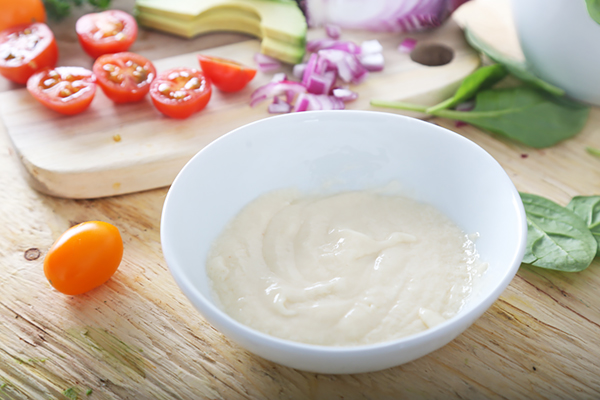 Whisked mayonnaise and sesame oil dressing in a small round bowl