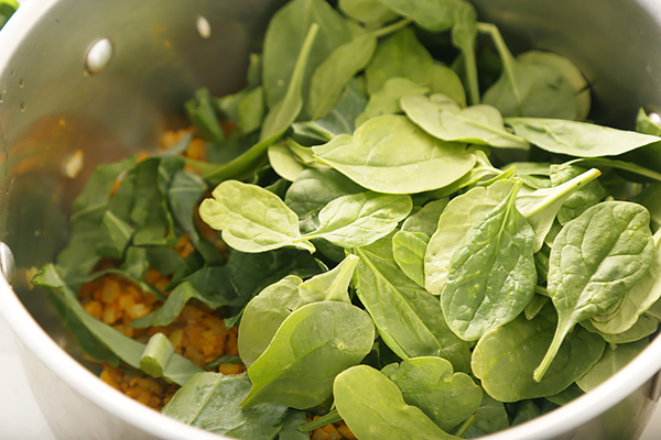Fresh spinach and swiss chard leaves piled into the pot over the sauteed aromatics