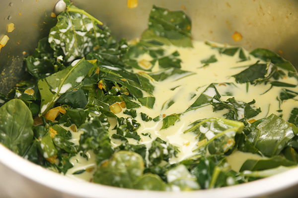 Heavy cream poured over wilted greens, chard, and onions in the soup pot