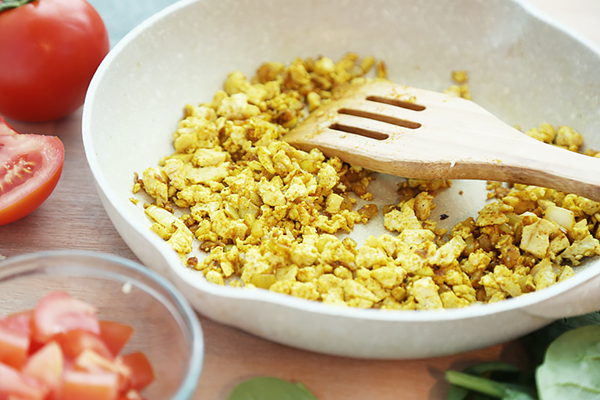 Crumbled tofu seasoned with turmeric, curry powder, and cumin in a skillet