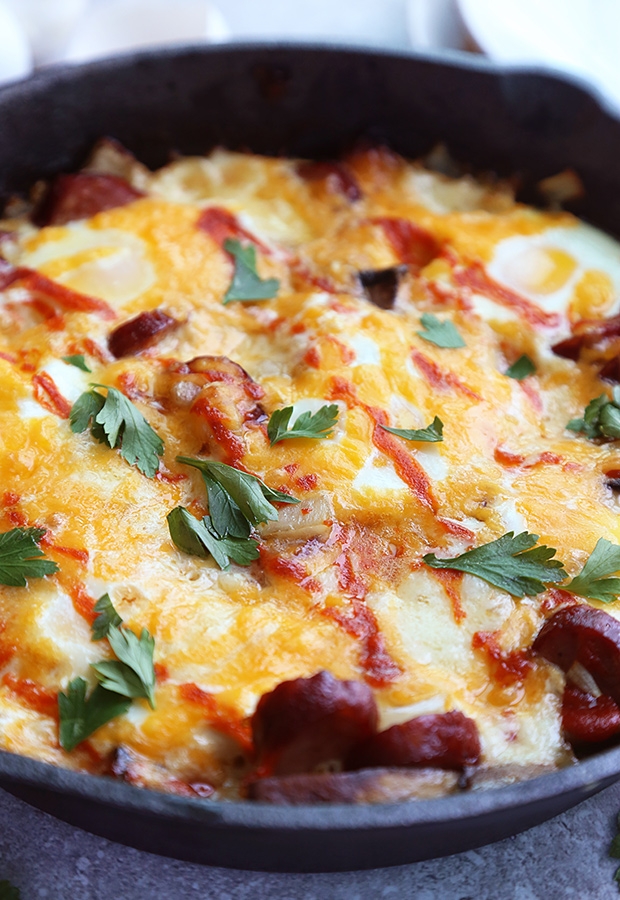Baked eggs with chorizo and melted cheddar in a cast iron skillet topped with sriracha