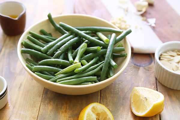 Steamed green beans tossed with lemon juice in a yellow bowl