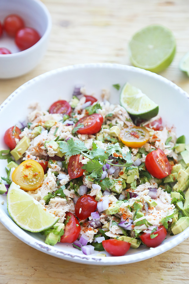Tuna ceviche tossed with avocado, cherry tomatoes, red onion, cilantro, and lime wedges