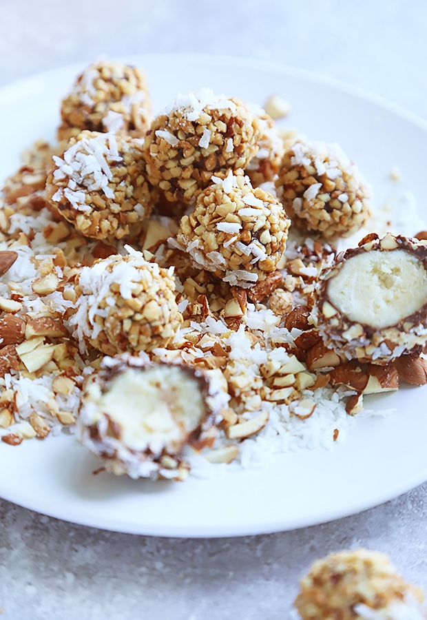 Almond cheesecake truffles coated in chopped almonds and shredded coconut with one cut open