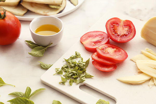 Sliced tomato rounds, julienned basil, and fresh mozzarella on a cutting board