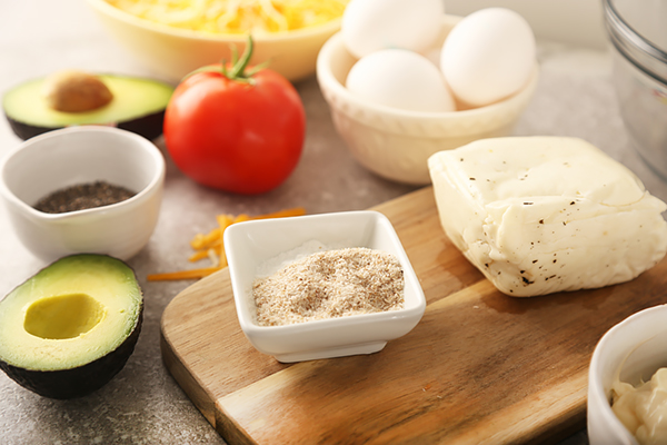 Halloumi cheese, avocado, eggs, psyllium husk, tomato, and cheddar gathered for assembly
