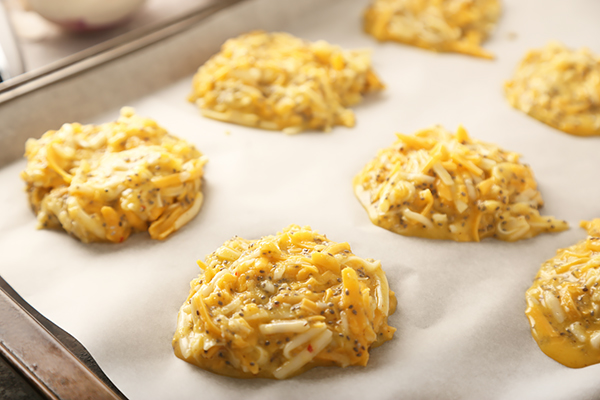 Eight cheese bun rounds portioned onto a parchment-lined baking sheet before baking