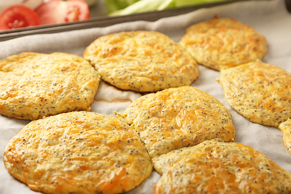 Golden baked cheddar buns with chia seed flecks cooling on parchment paper