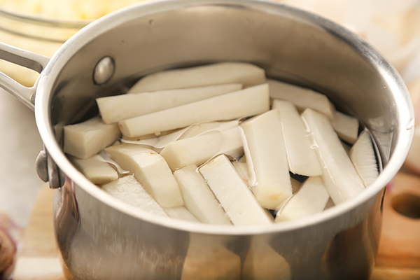 Rutabaga fries boiling in salted water inside a stainless steel pot
