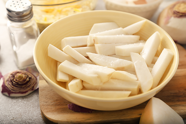 Parboiled rutabaga fries tossed with coconut oil in a yellow bowl