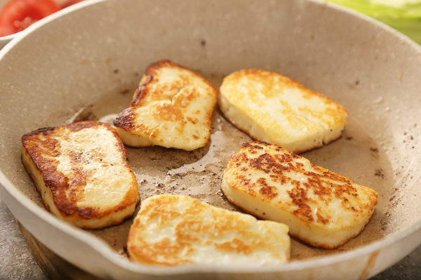 Halloumi cheese slices frying golden brown in butter in the pan