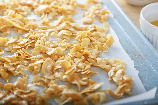 Coated coconut flakes spread across a parchment-lined baking sheet before baking