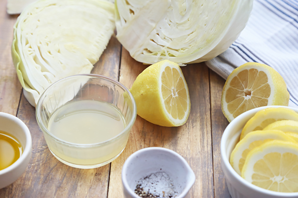 Green cabbage, fresh lemons, lemon juice, olive oil, and salt and pepper laid out for roasting
