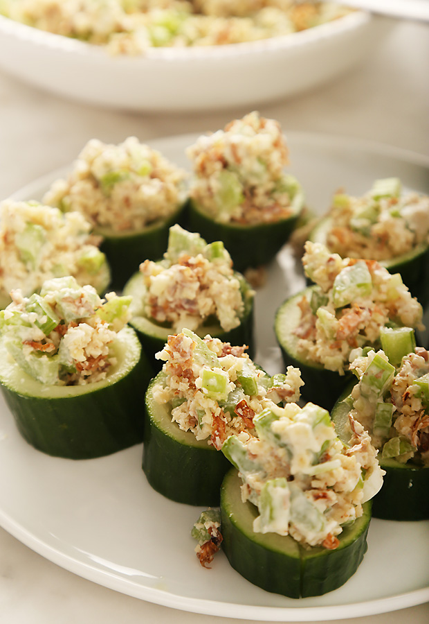 Almond tuna salad spooned into thick cucumber rounds on a white plate