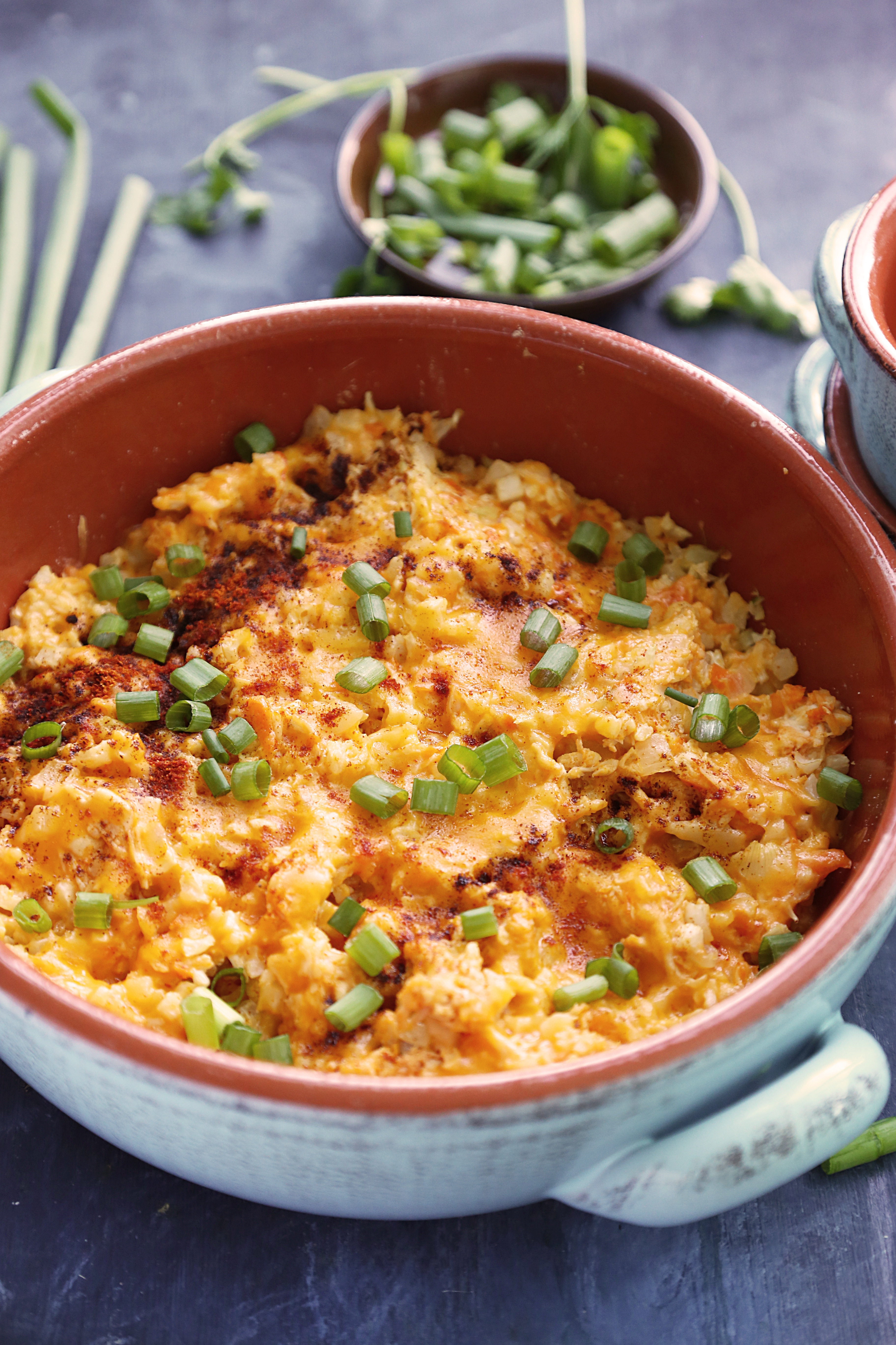 Buffalo chicken cauliflower mac topped with browned cheddar, smoked paprika, and sliced green onions