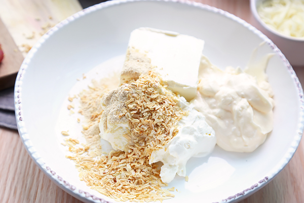 Cream cheese, cottage cheese, sour cream, and grated parmesan in a large white mixing bowl