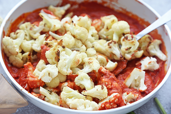 Roasted cauliflower florets folded into the creamy tomato parmesan sauce in the pan