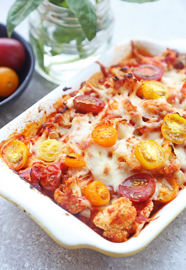 Baked caprese cauliflower casserole with browned mozzarella and roasted cherry tomatoes in a white dish