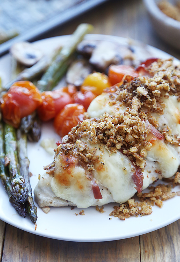 Thin-cut hasselback chicken with crushed pork rinds served with roasted asparagus and blistered tomatoes