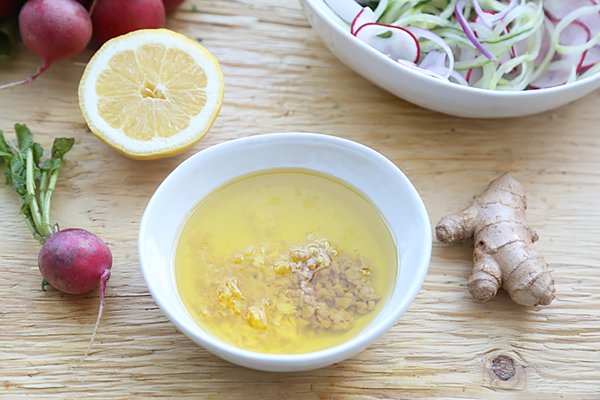 Lemon ginger dressing with minced garlic and olive oil in a small ceramic bowl