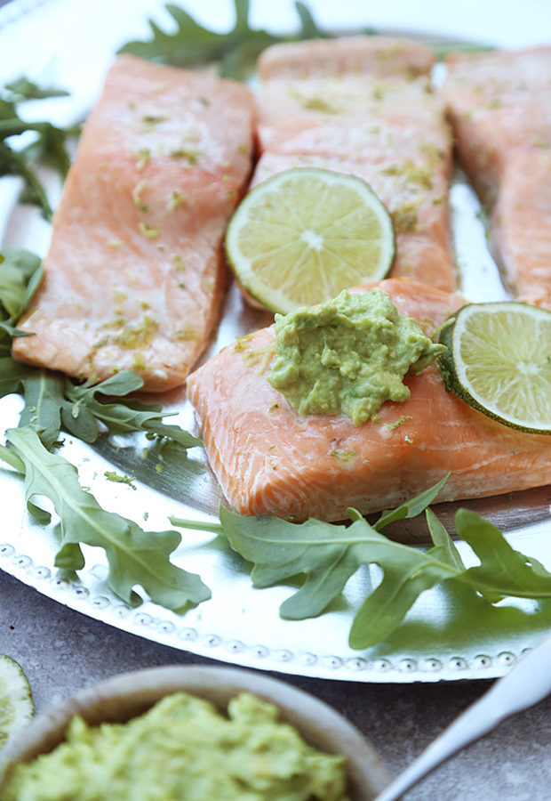 Grilled salmon fillets with avocado mayo and lime slices on a bed of arugula