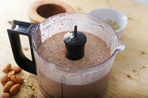 Tofu, cocoa powder, and coconut milk blended into a thick chocolate mixture in a food processor