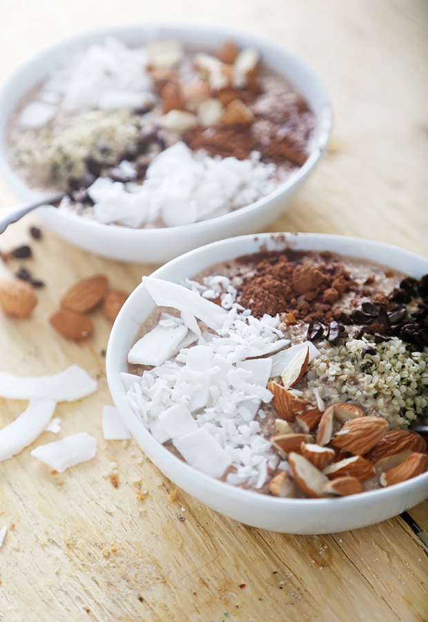 Two chocolate smoothie bowls topped with coconut flakes, cacao nibs, almonds, and hemp hearts