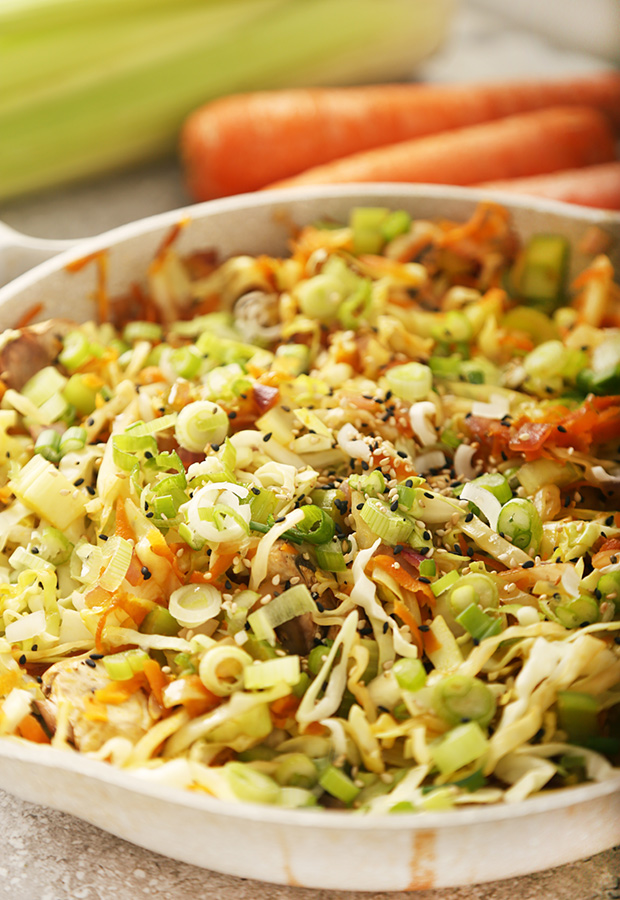 Egg roll in a bowl topped with sliced green onions and black and white sesame seeds