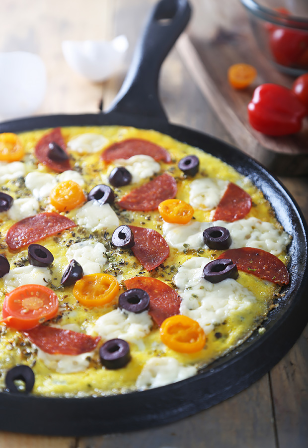 Broiled breakfast pizza with browned mozzarella, pepperoni, and oregano in a cast iron skillet