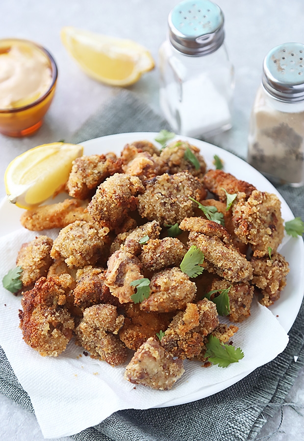 Pile of browned fried chicken nuggets with protein powder coating on a white plate