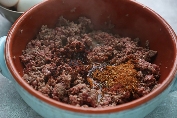 Browning ground beef with taco seasoning and chili powder in an oven-safe skillet