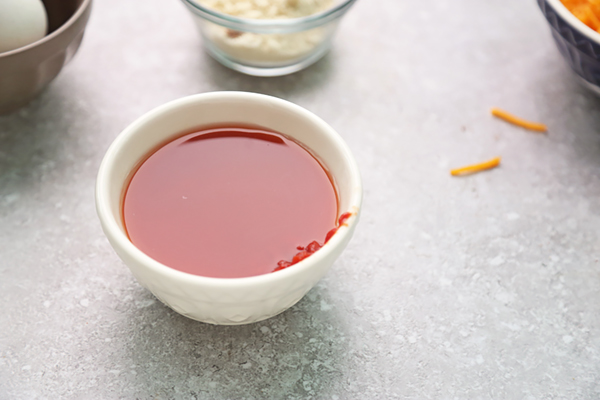 Tomato paste and water mixed into a reddish sauce in a small white bowl