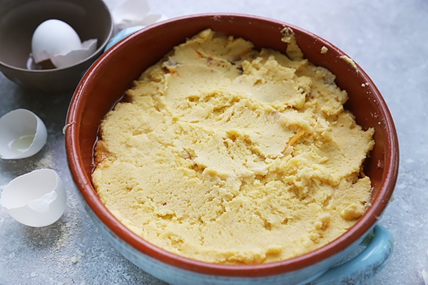 Almond flour batter spread over the seasoned beef filling in a ceramic skillet