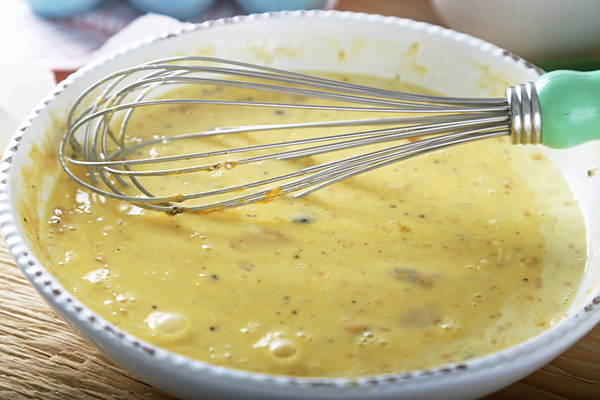 Eggs whisked with heavy cream, garlic powder, and black pepper in a bowl